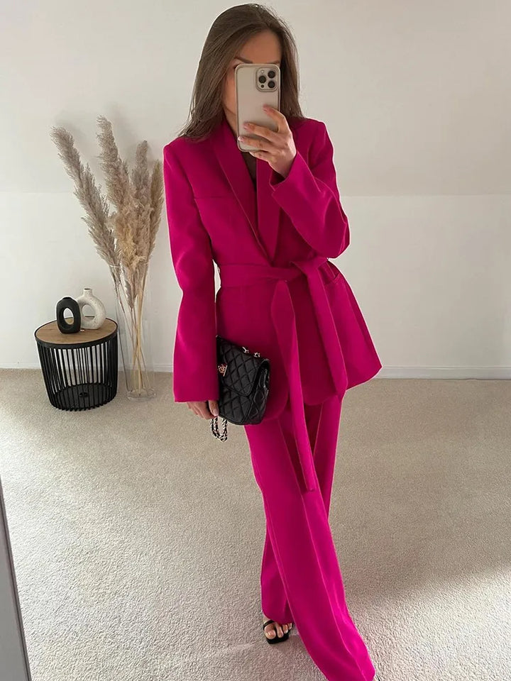Frau in pinkem Damenanzug mit Blazer und Hose, modisch, elegant, Selfie, Innenraum.