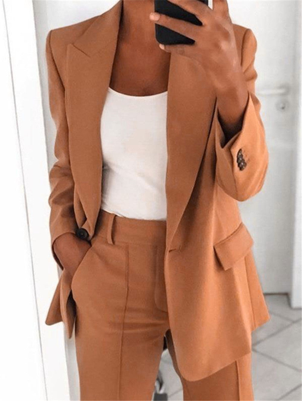 Frau im braunen Anzug mit weißem Top, Businessmode, eleganter Damenblazer, Bürooutfit.