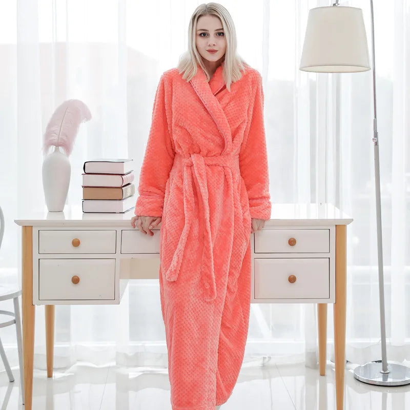 Frau im rosa Fleece-Bademantel, stehend vor weißem Schreibtisch mit Büchern und Lampe.