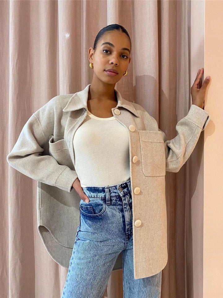 Frau in beiger Jacke und Jeans vor Vorhang, modische Damenbekleidung, lässiger Stil.