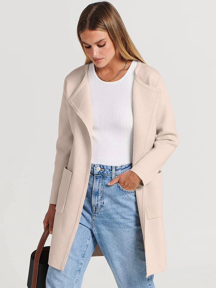 Frau in beigem Wollmantel, weißem Oberteil und blauer Jeans, modisch, elegant, Herbstmode.