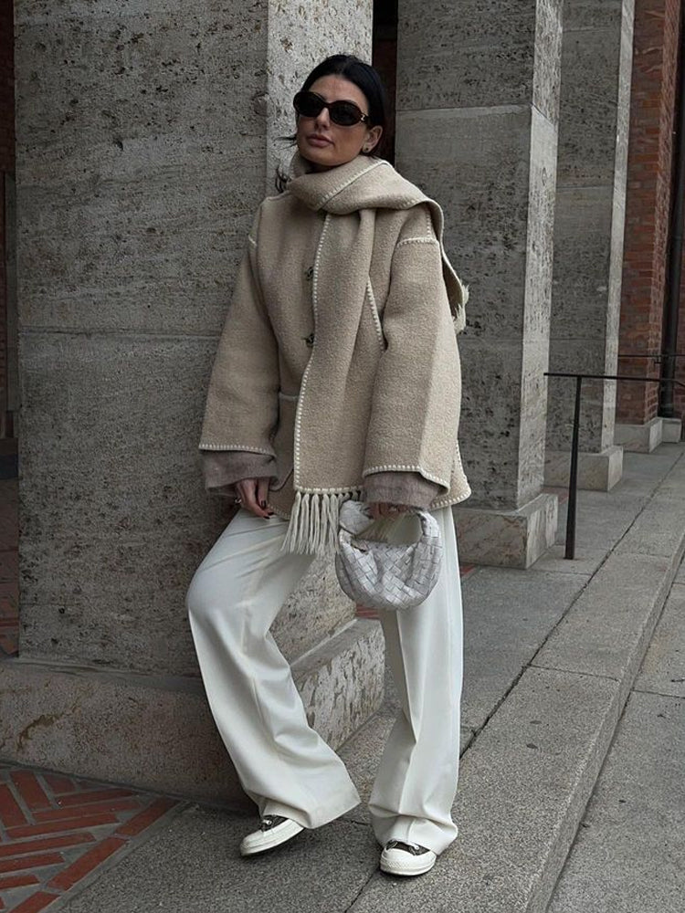 Frau in beiger Wolljacke mit Schal, weiße Hose, Sonnenbrille, modisch, Herbstmode.