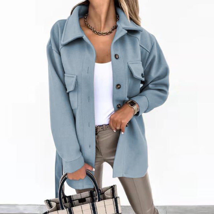 Frau in blauer Jacke, weißem Top, beige Hose, hält karierte Handtasche, modisch, elegant.