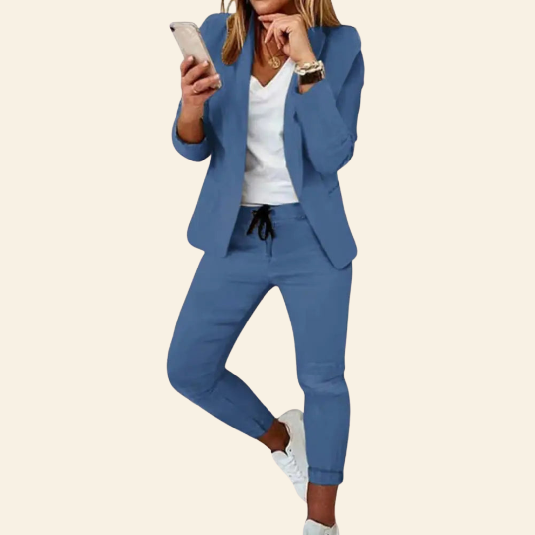 Frau in blauem Anzug mit Smartphone, weißem T-Shirt, Sneakers, Business-Casual-Look.