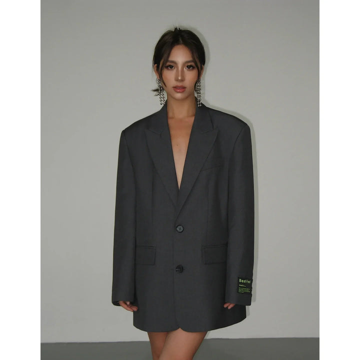 Frau in grauem Oversize-Blazer, Büro-Look, modische Damenbekleidung, eleganter Stil.