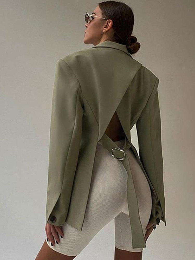 Frau in olivgrünem Blazer mit offenem Rücken, weiße Radlerhose, modisch, elegant.