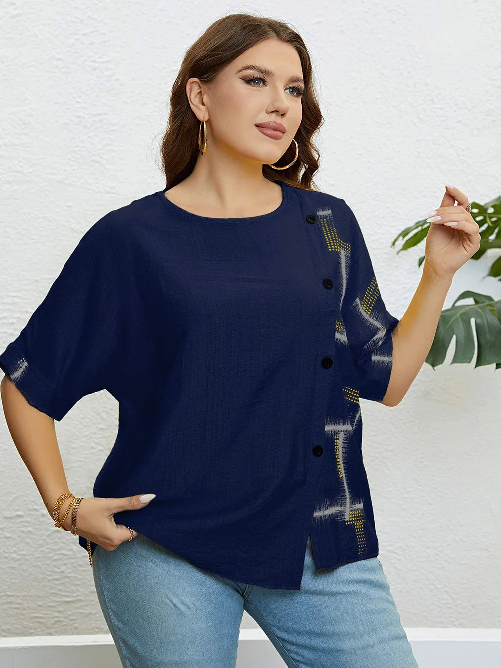 Frau in dunkelblauer Bluse mit Knöpfen und Muster, goldene Ohrringe, lässiger Look.