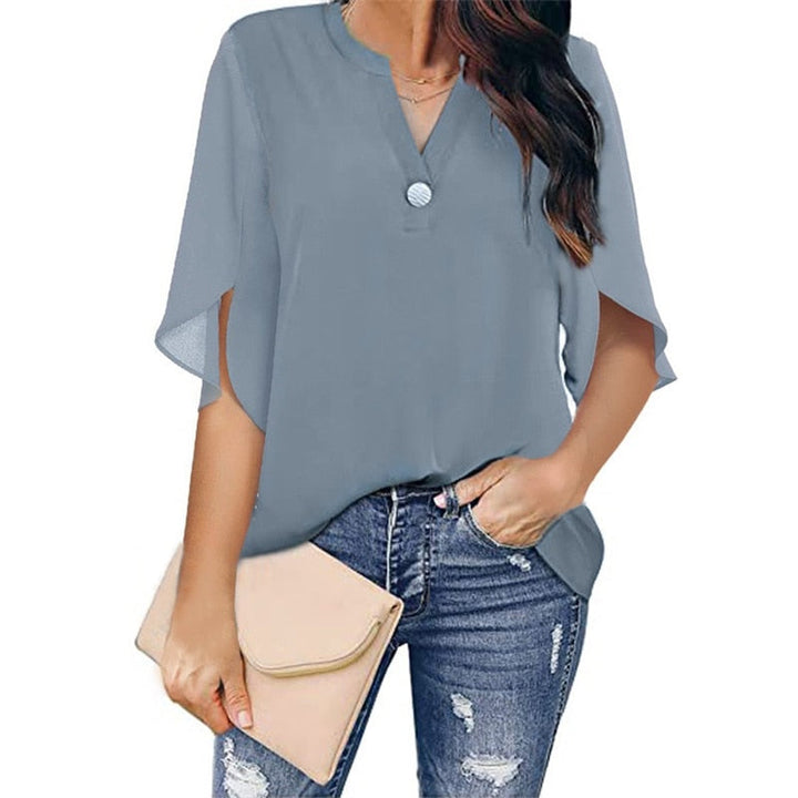 Frau in blauer Bluse mit V-Ausschnitt, zerrissene Jeans, beige Clutch, modisch, lässig.