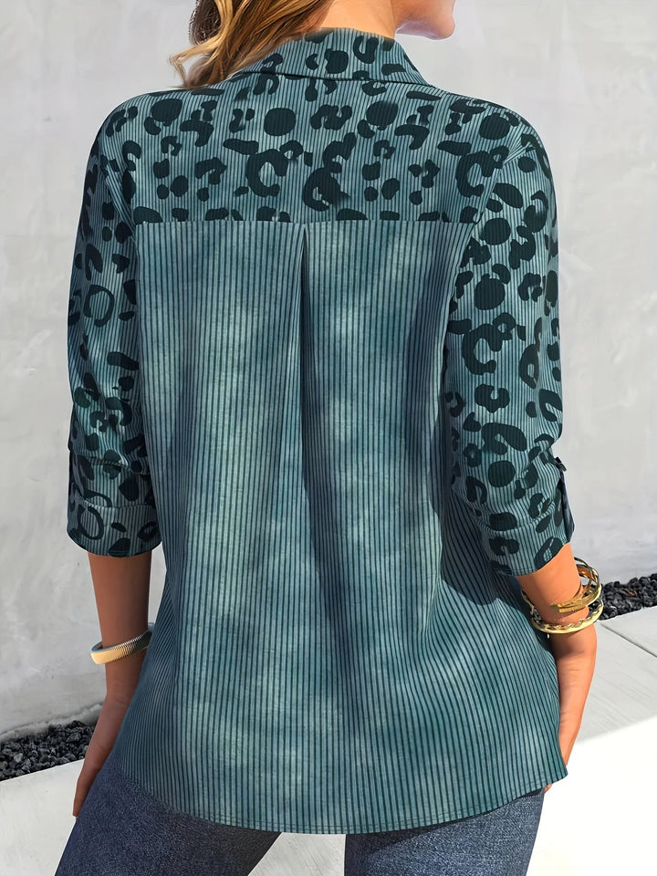 Frau in blau-grünem, gemustertem Hemd mit 3/4-Ärmeln und Jeans von hinten.