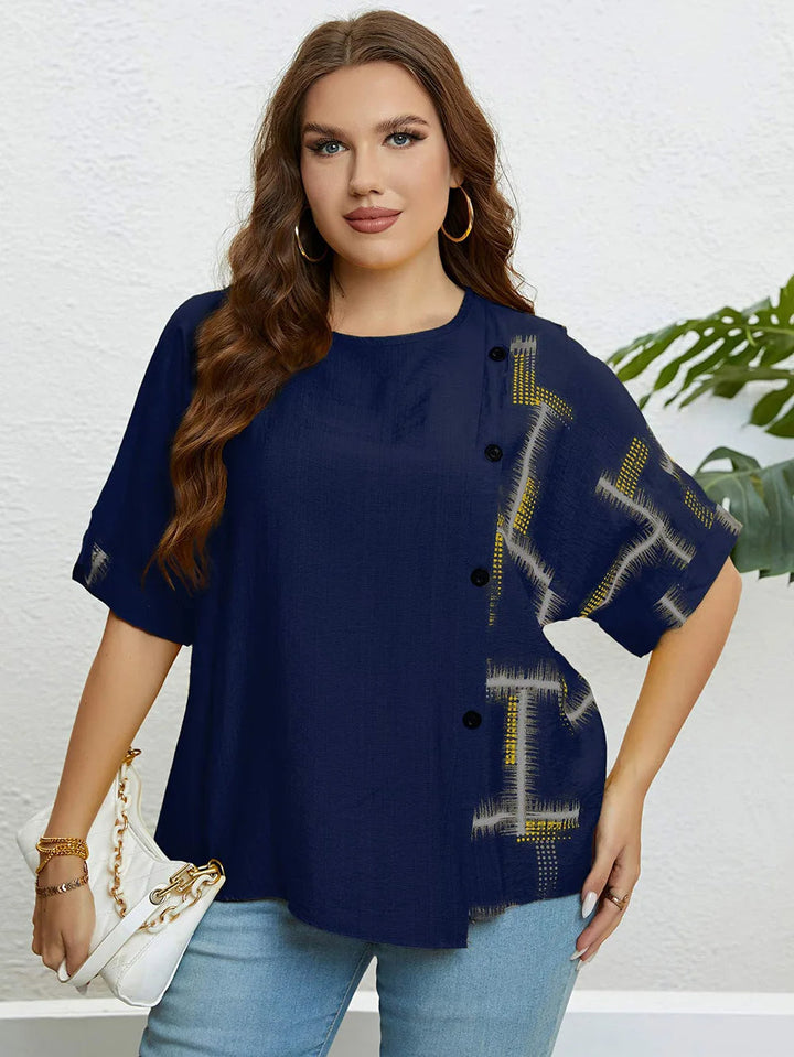 Frau in dunkelblauer Bluse mit Knöpfen, Jeans und weißer Handtasche vor weißer Wand.