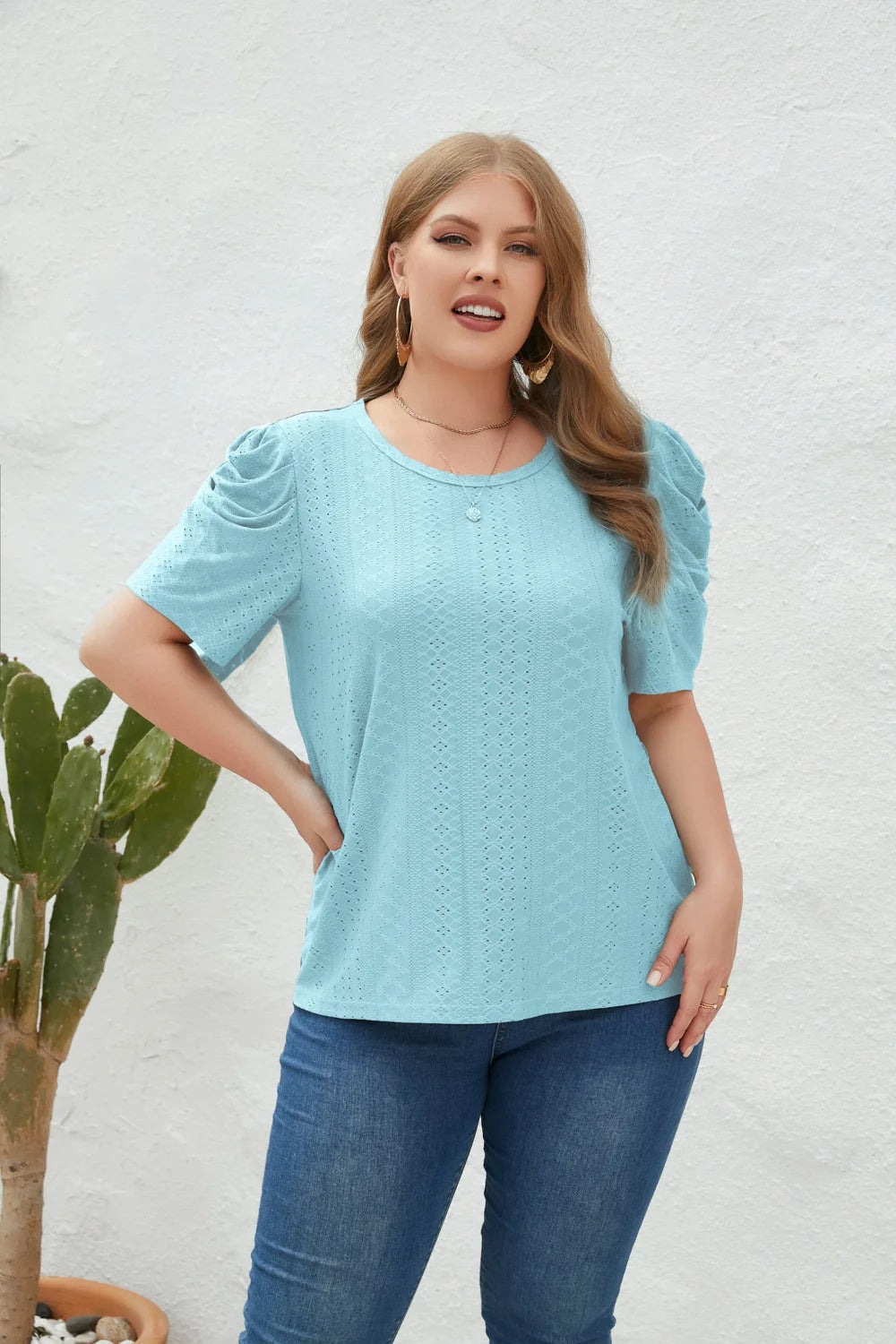 Frau in hellblauer Spitzenbluse und Jeans vor weißer Wand, Mode, Damenbekleidung, Freizeitlook.