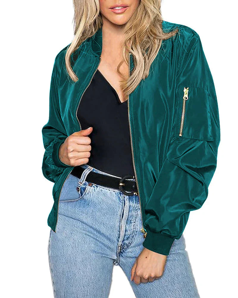 Frau in grüner Bomberjacke aus Satin, schwarze Bluse, blaue Jeans, modisch, lässiger Stil.