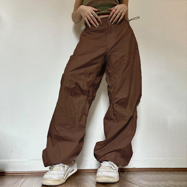 Frau trägt braune Baggy-Hose, weiße Sneaker, lässiger Stil, modische Damenbekleidung.