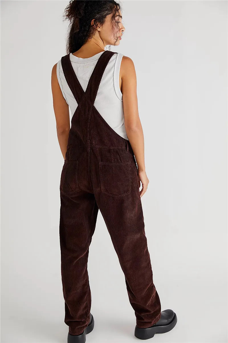 Frau in brauner Cord-Latzhose, weißem Tanktop, schwarze Schuhe, Rückansicht.