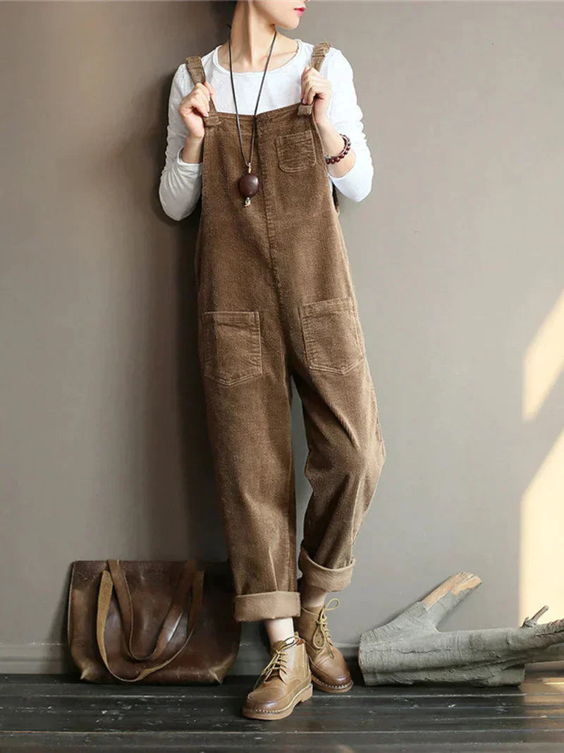 Frau in braunem Cord-Overall, weißem Shirt, braunen Stiefeln, mit Ledertasche, lässiger Look.