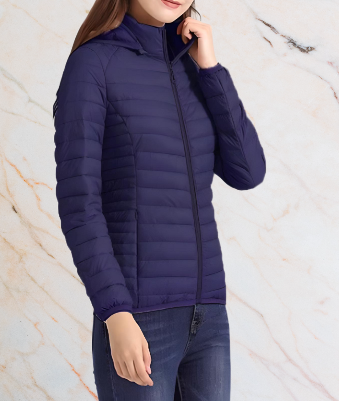 Frau in dunkelblauer Steppjacke, Reißverschluss, Kapuze, lässiger Stil, Marmorhintergrund.