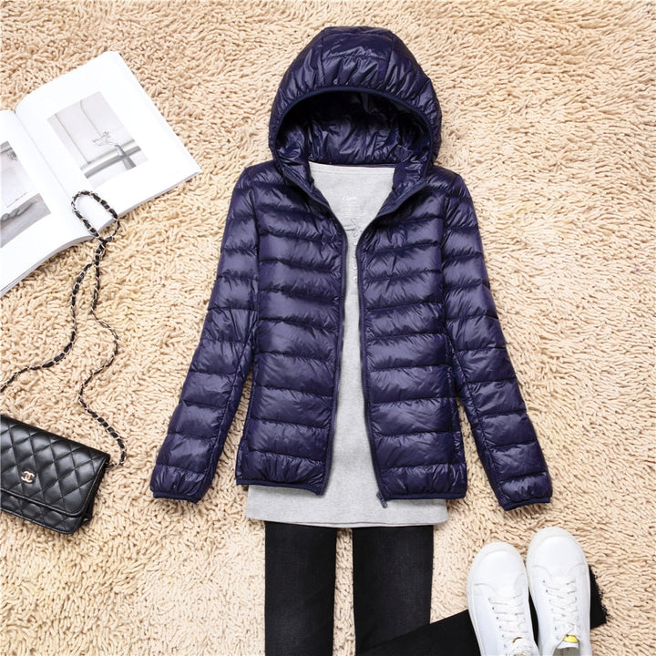 Dunkelblaue Daunenjacke mit Kapuze, Damenmode, Winterjacke, auf Teppich mit Accessoires.