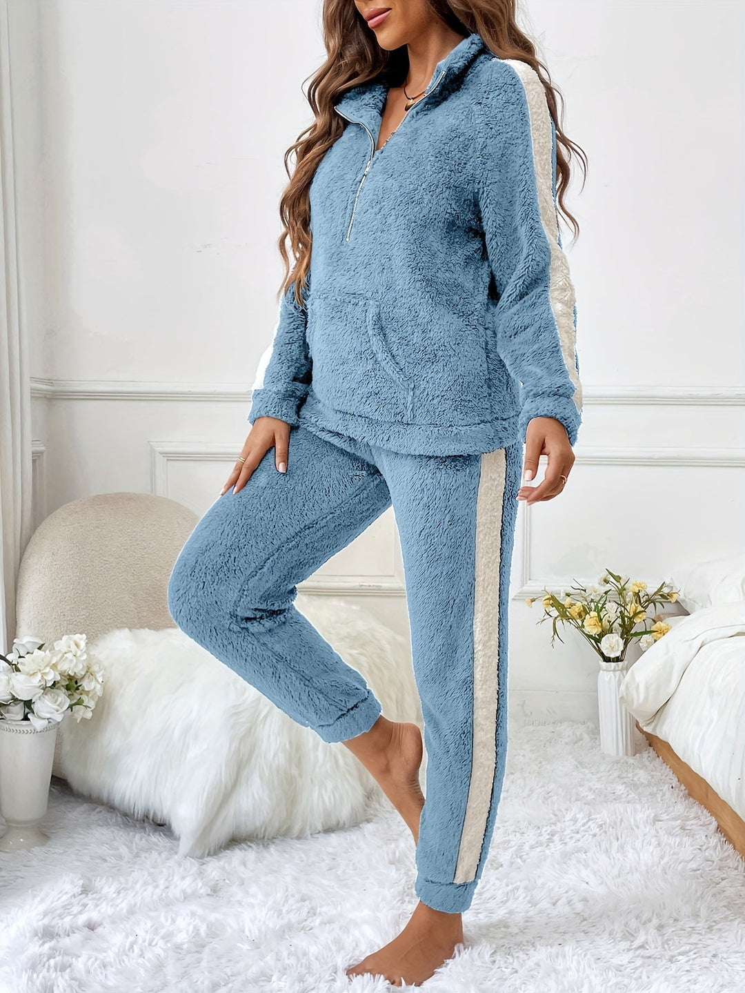 Frau in blauem Fleece-Trainingsanzug mit weißen Streifen, gemütlich, modisch, Wohnzimmer.