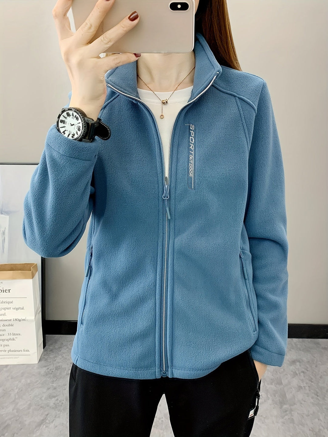 Frau in blauer Fleecejacke mit Reißverschluss, Sportuhr, lässiger Stil, Innenaufnahme.