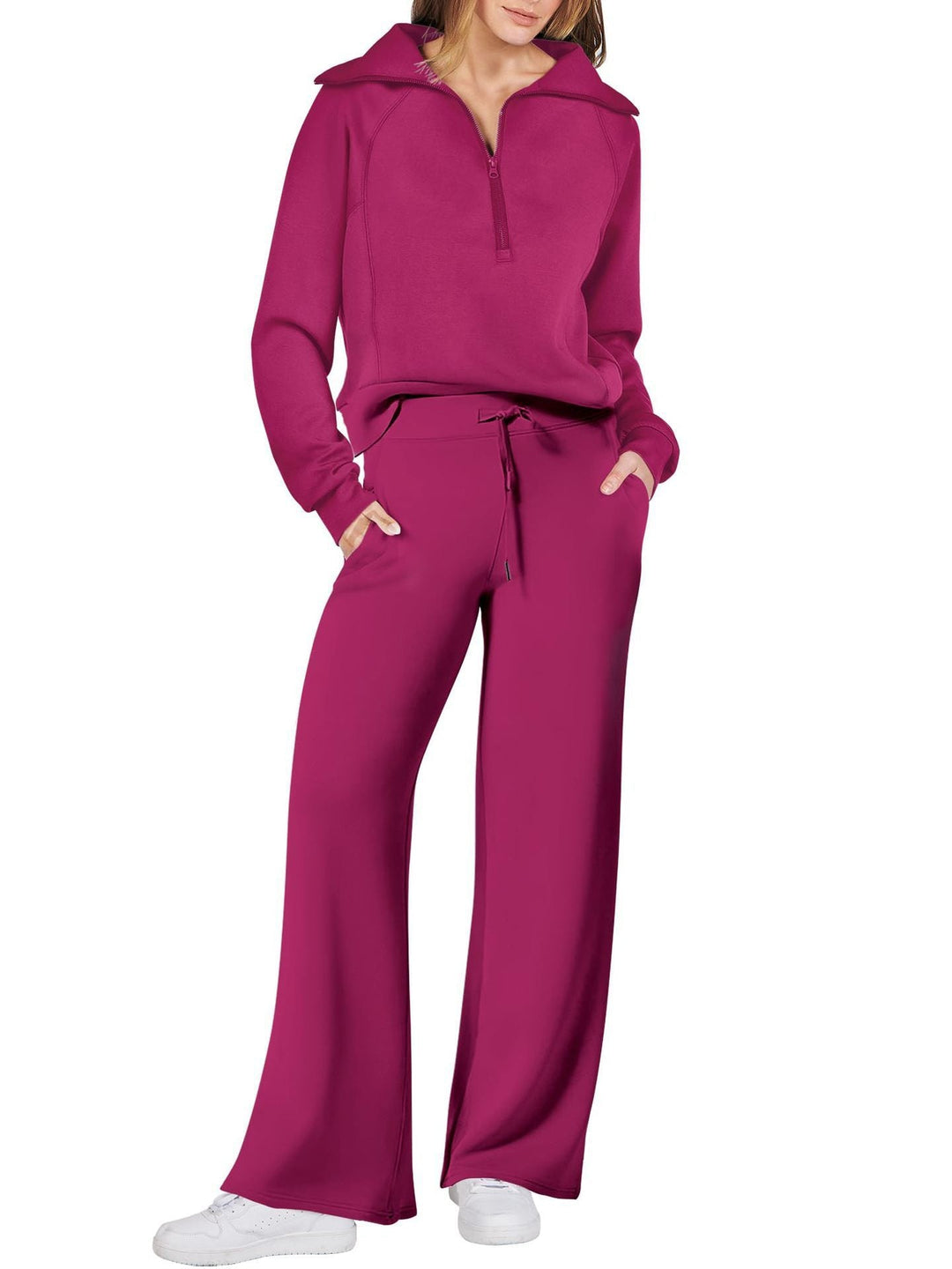 Frau in fuchsiafarbenem Freizeitanzug mit weitem Schnitt und weißen Sneakers.