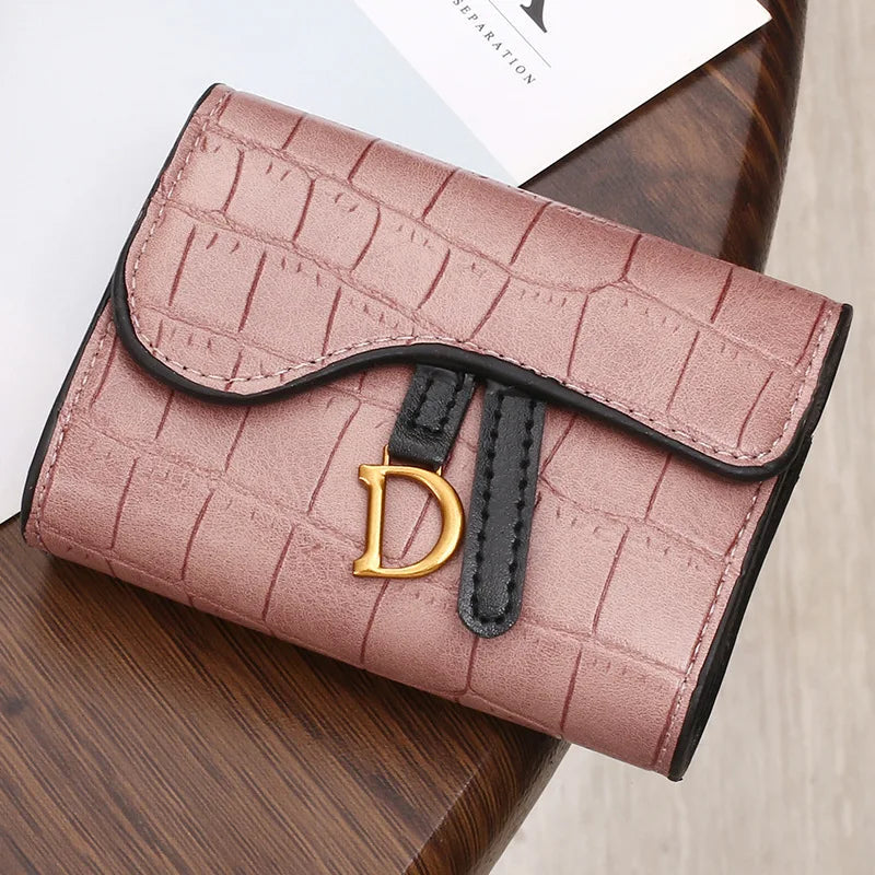 Rosa Damen-Geldbörse aus Kunstleder mit Krokodilprägung und goldfarbenem D-Logo.