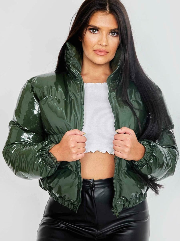Frau in glänzender, grüner Steppjacke, weißem Top und schwarzer Hose, Mode, Winterjacke.