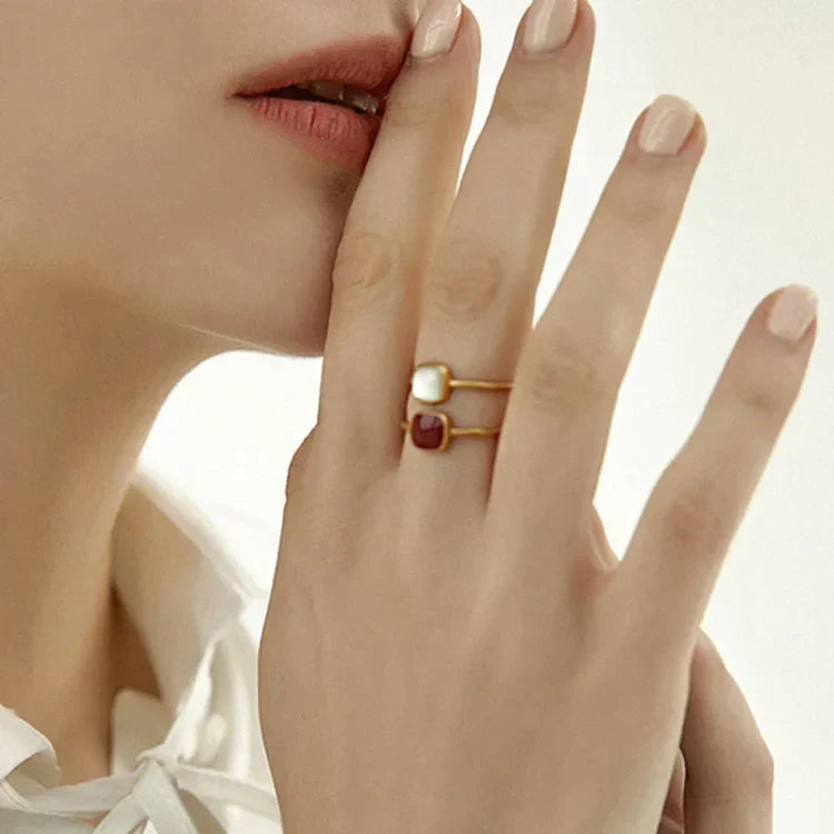 Frau trägt goldene Ringe mit quadratischen Steinen, eleganter Schmuck, Nahaufnahme.