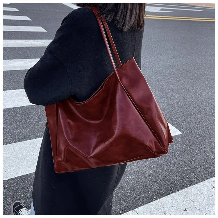 Frau mit großer brauner Ledertasche auf Straße, modisches Accessoire, elegantes Design.