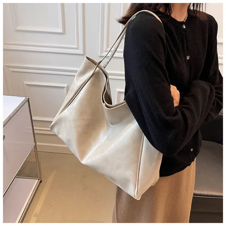 Frau mit großer, weißer Ledertasche, elegantes Design, modisches Accessoire, Innenraum.