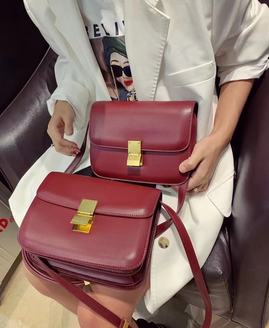 Damenhandtasche aus rotem Leder mit goldener Schnalle, elegant und modisch.