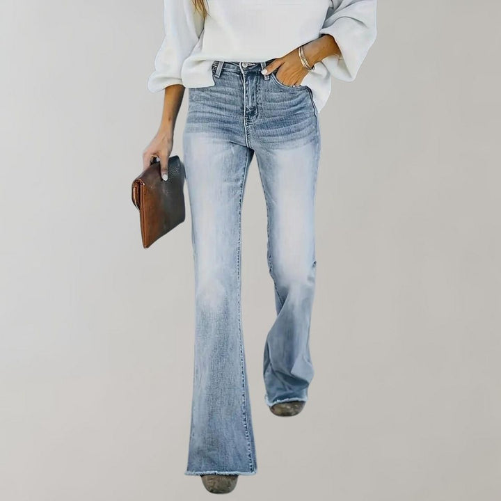 Frau in blauer Schlagjeans und weißem Pullover, hält braune Clutch, modisch, lässiger Stil.