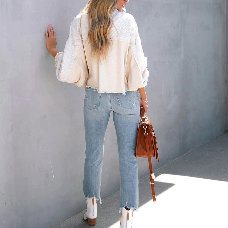 Frau in weißem Pullover und blauer Jeans mit brauner Tasche, lässige Mode, Rückansicht.