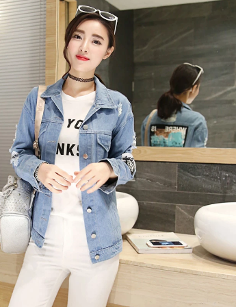 Frau in blauer Jeansjacke, weißem T-Shirt und weißer Hose, modisch, lässig, urbaner Stil.