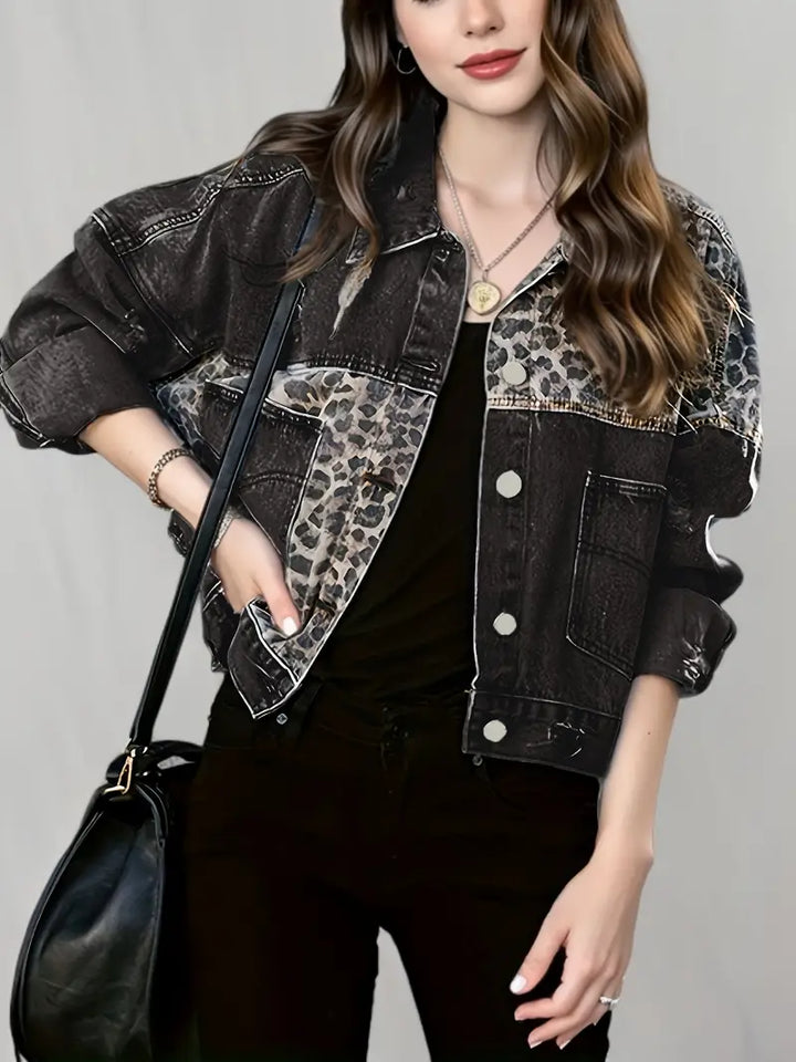 Frau in schwarzer Jeansjacke mit Leopardenmuster, schwarze Hose, schwarze Tasche, lässiger Look.