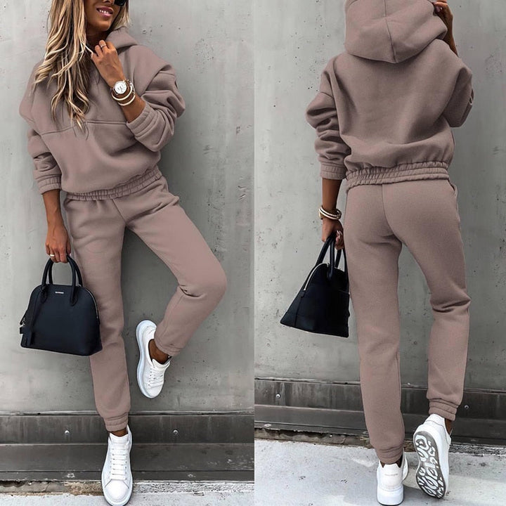 Frau in braunem Hoodie-Set, weiße Sneaker, schwarze Handtasche, lässige Mode.