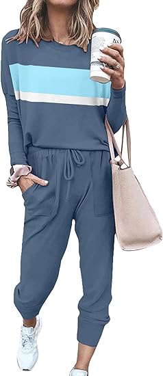 Frau in blauem Jogginganzug mit Streifen, hält Kaffeebecher, trägt beige Tasche und weiße Sneaker.