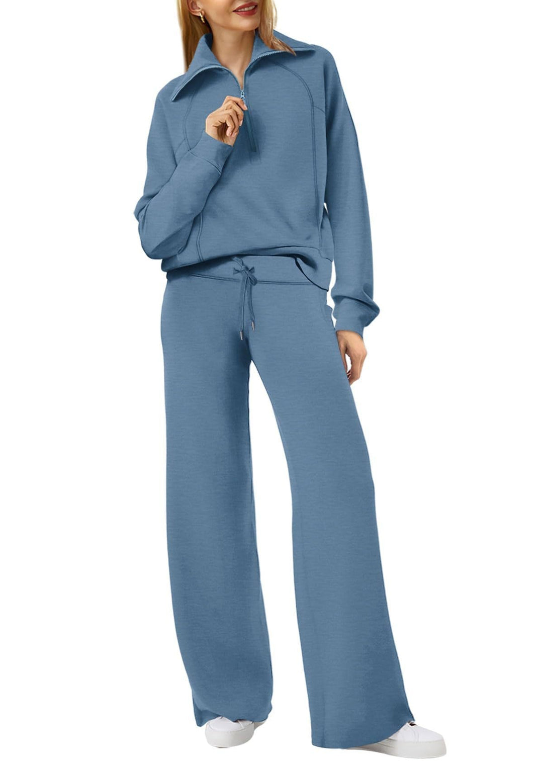 Frau in blauem Jogginganzug mit Reißverschluss, weite Hose, Freizeitmode, bequeme Kleidung.