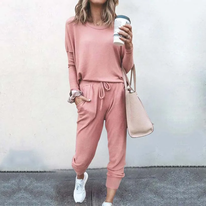 Frau in rosa Freizeitanzug mit Kaffeebecher und Tasche, lässige Mode, bequeme Damenbekleidung.