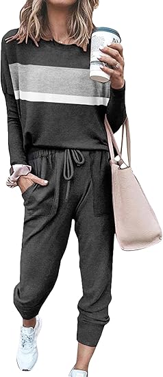 Frau in grauem Jogginganzug mit Streifen, hält Kaffeebecher, trägt beige Tasche und weiße Sneaker.