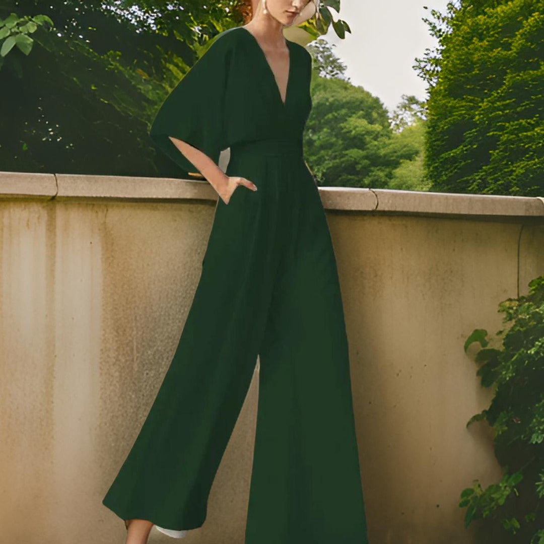 Damen-Jumpsuit, dunkelgrün, V-Ausschnitt, weite Ärmel, elegant, Sommermode, Gartenhintergrund.