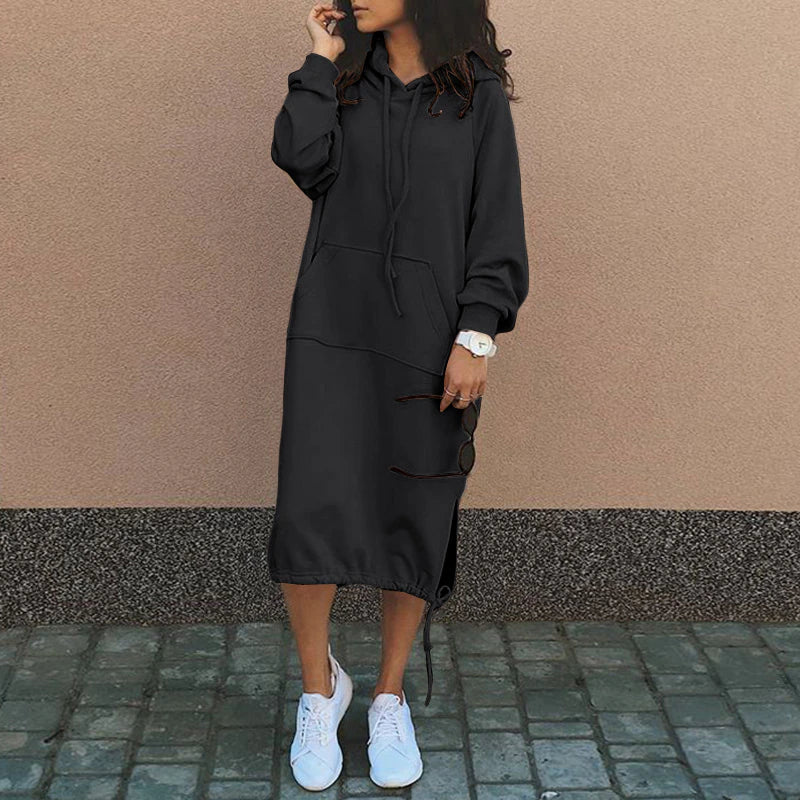 Frau in schwarzem Hoodie-Kleid, weiße Sneaker, lässiger Stil, Herbstmode, Straßenhintergrund.