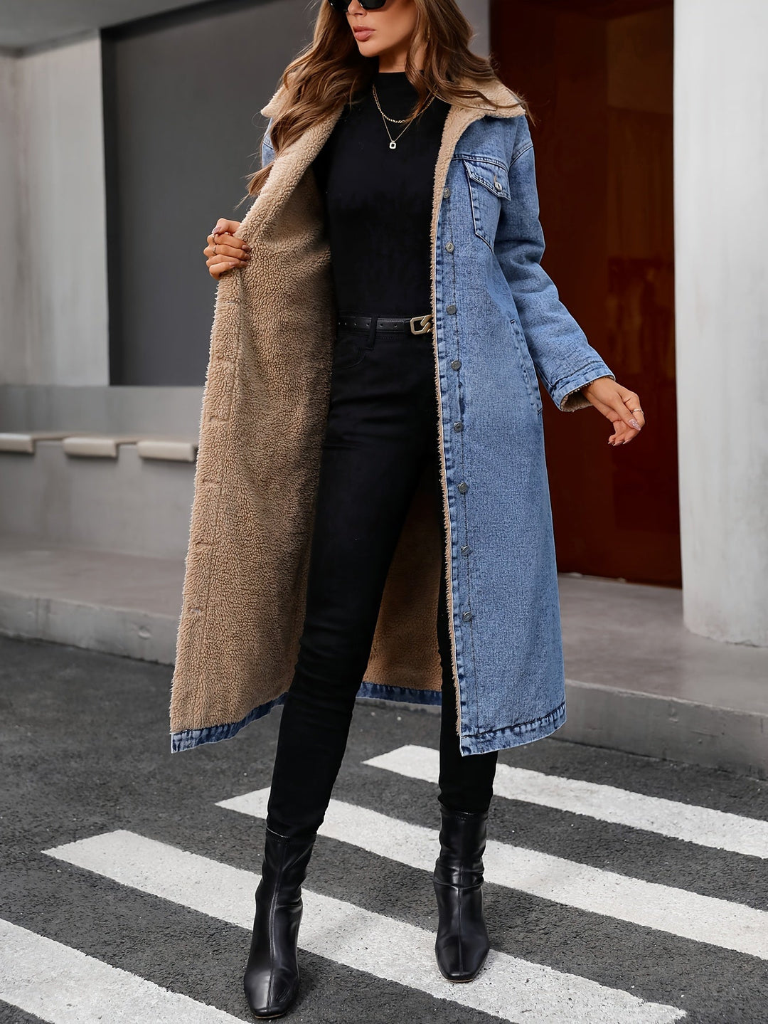 Frau in langer Jeansjacke mit Fellfutter, schwarze Stiefel, modisch, urbaner Stil.