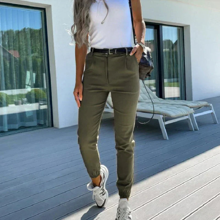 Frau in olivgrüner Hose und weißem Top auf Terrasse, lässiger Sommerlook, Mode für Damen.