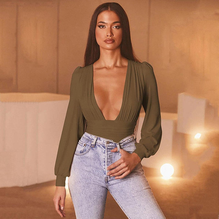 Frau in olivgrünem V-Ausschnitt-Body mit langen Ärmeln und blauen Jeans, modisch, elegant.