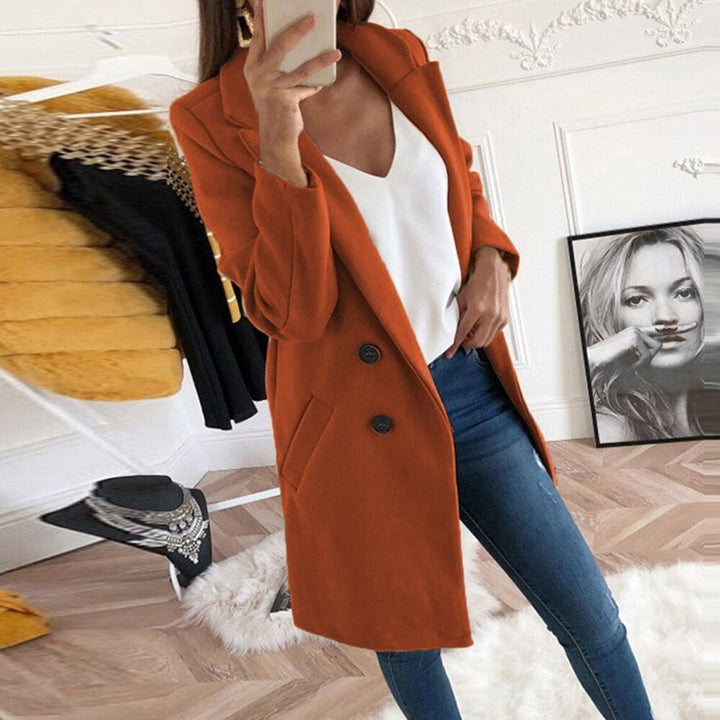 Frau in orangefarbenem Mantel, weißem Top, blauer Jeans, modernes Wohnzimmer, modisch.