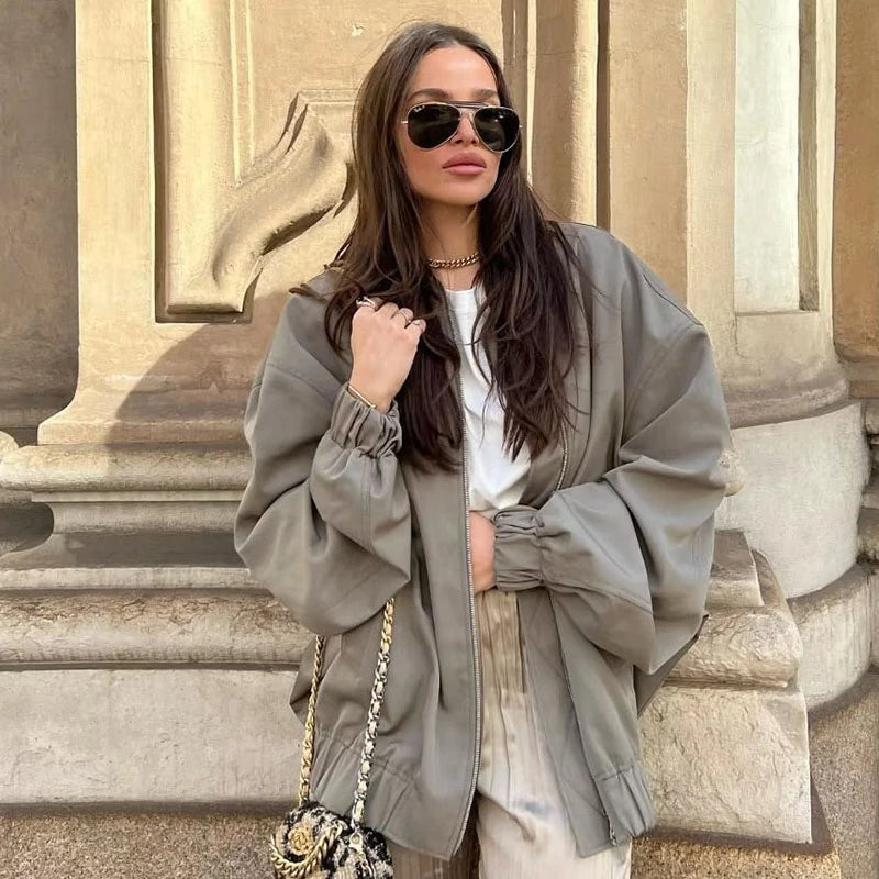Frau in übergroßer, grauer Herbstjacke, Sonnenbrille, modische Handtasche, lässiger Stil.