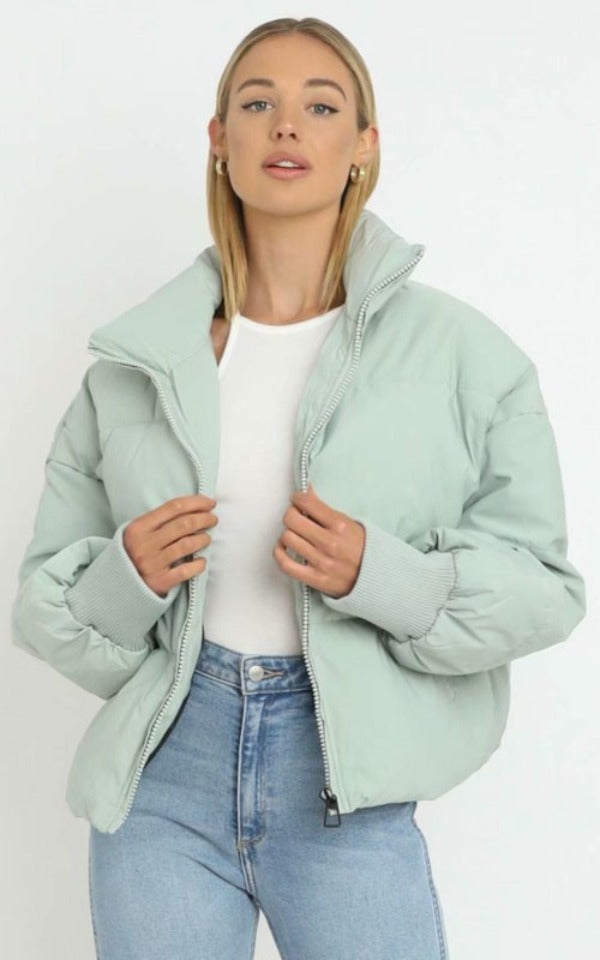 Frau in mintgrüner Daunenjacke, weiße Bluse, blaue Jeans, Mode, Winterkleidung, Damenbekleidung.