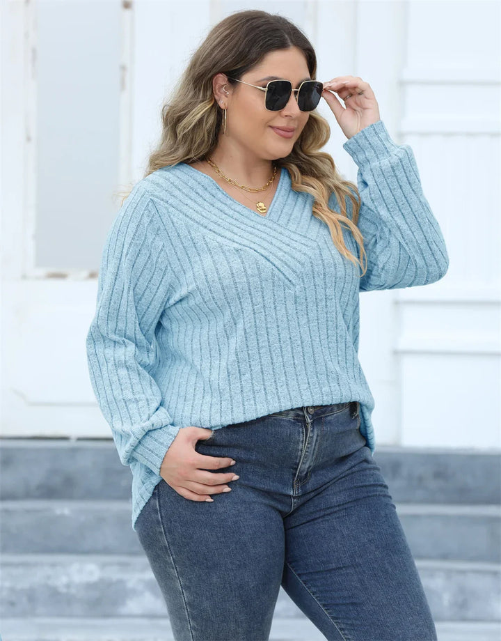 Frau in hellblauem Strickpullover und Jeans, trägt Sonnenbrille, lässige Mode.