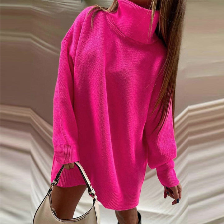 Frau in pinkem Rollkragenpullover, hält weiße Handtasche, modisch, Herbstmode.