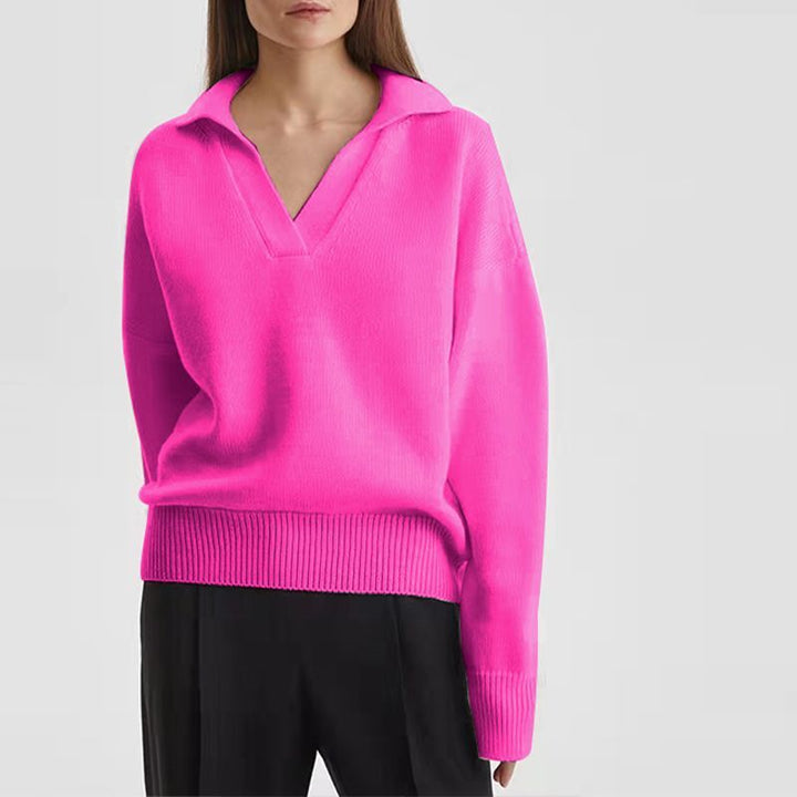 Frau in pinkem Pullover mit V-Ausschnitt, lange Ärmel, schwarze Hose, modisch, lässig.
